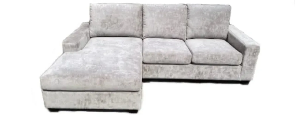 A pale grey crushed velvet chaise sectional, seen from the front with the chaise on the left