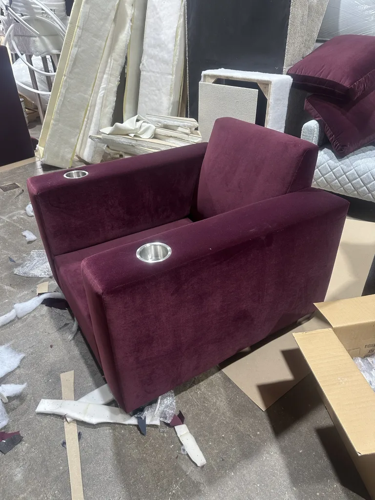 A burgundy velvet theatre seat with a stainless cup holder set into each arm