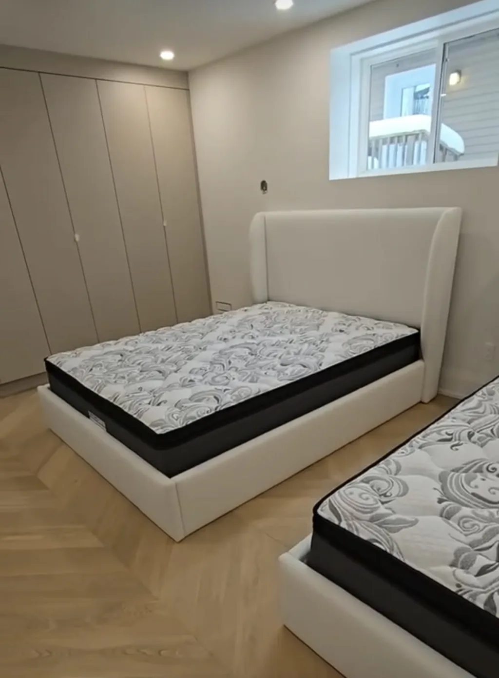 Two cream upholstered bed frames with wing headboards in a finished bedroom