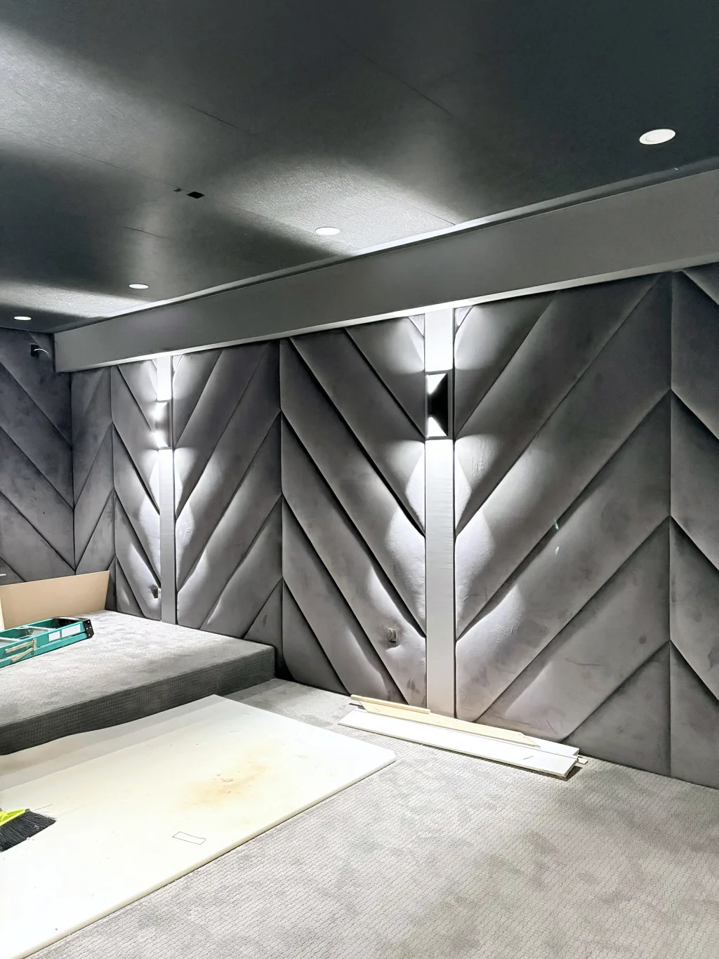 The panelling and its metal light strips in place, with the sconces already washing the chevrons